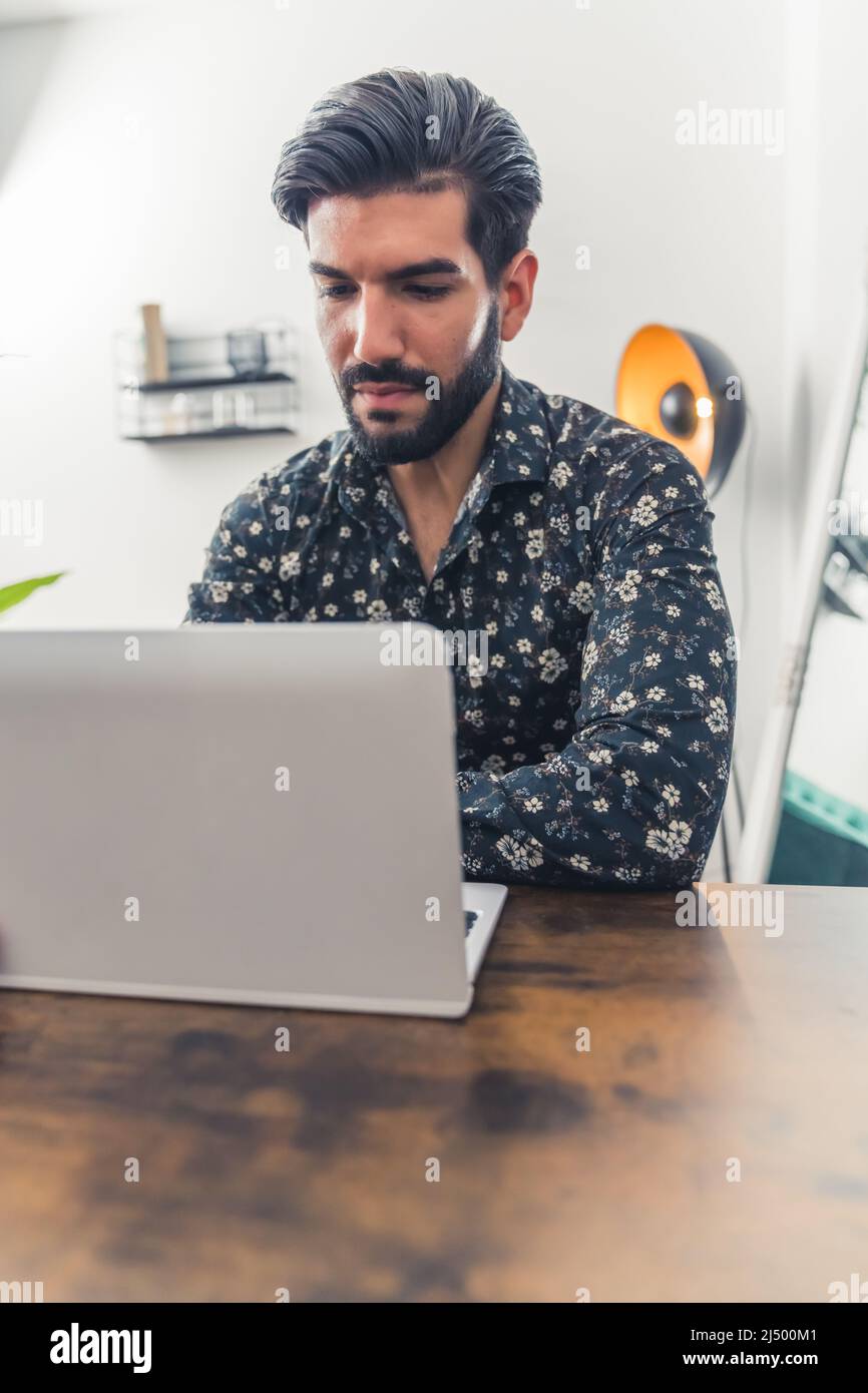 Giovane uomo caucasico che lavora dall'ufficio sul suo laptop. Foto di alta qualità Foto Stock