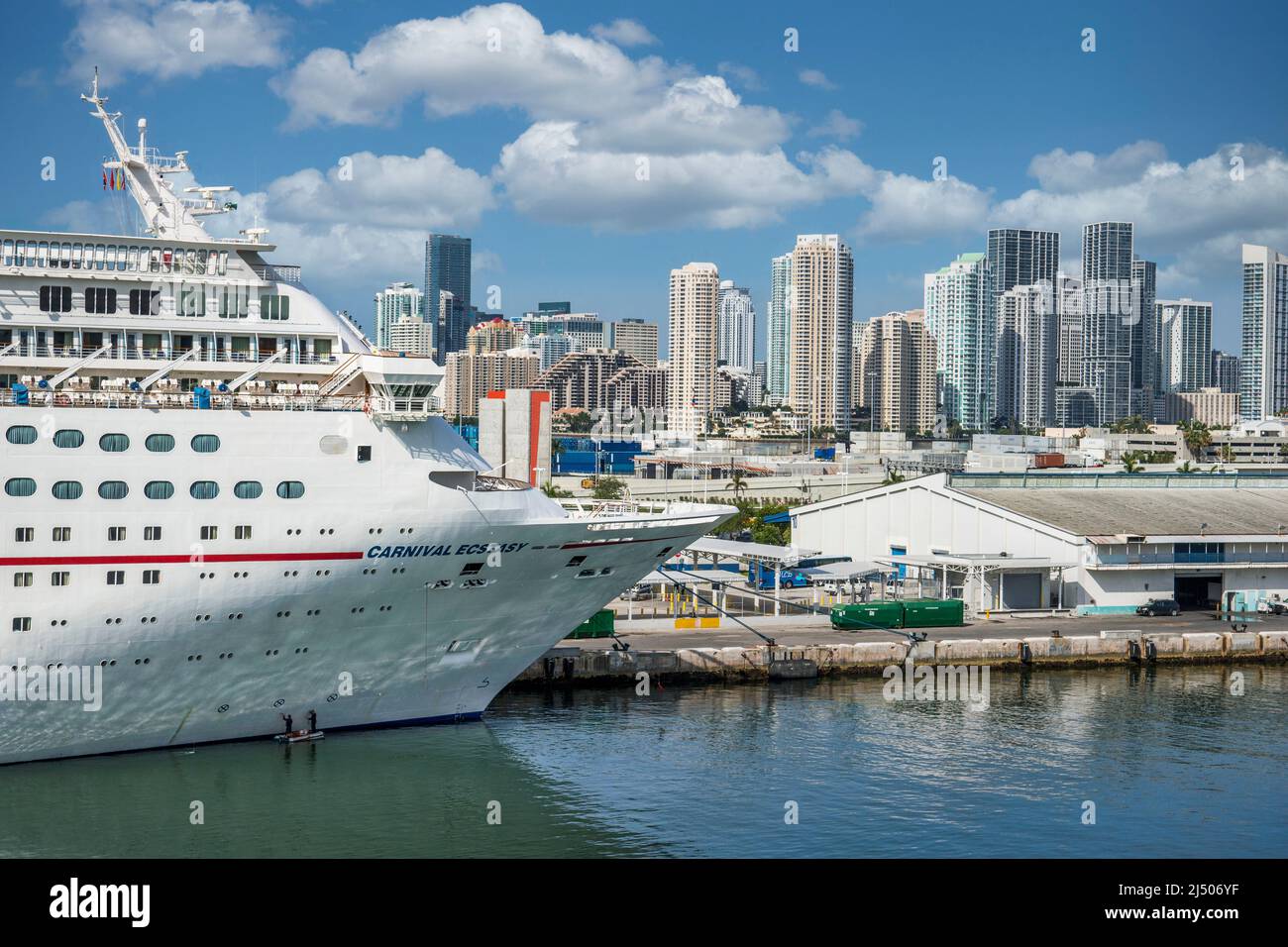 Una vista a prua dell'estasi della Carnival Cruise Line, ancorata al Porto di Miami con lo skyline di Miami sullo sfondo. Foto Stock