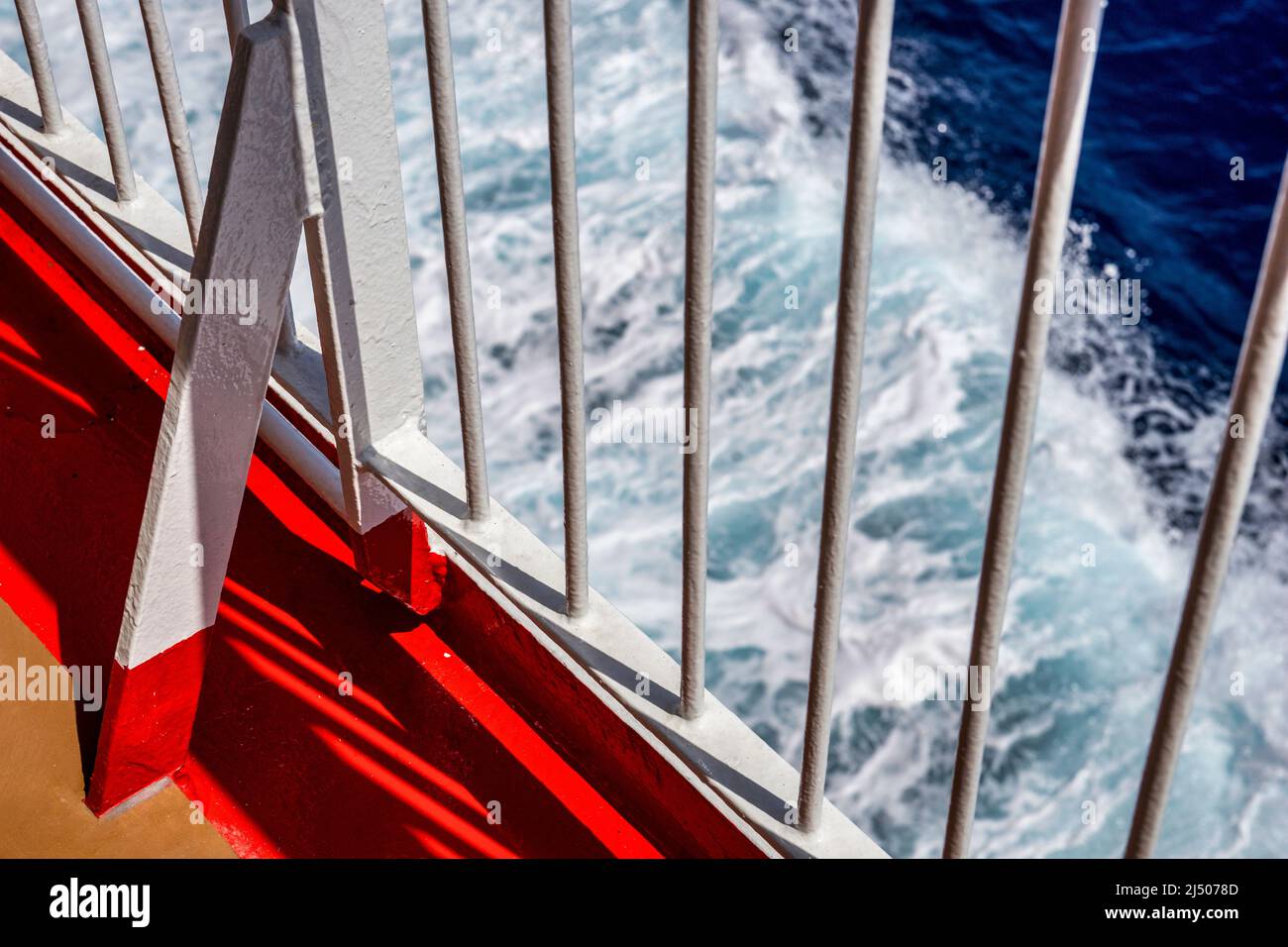 Il ponte e la ferrovia con l'oceano che passa in fretta formano un modello colorato sulla nave da crociera Bimini Superfast nelle Bahamas. Foto Stock