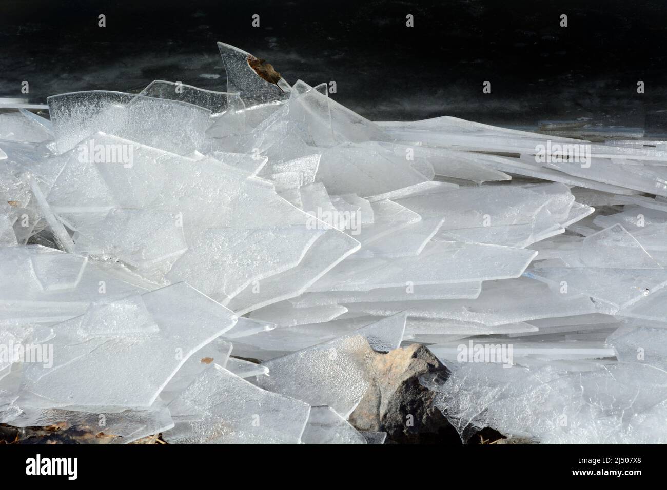 Fogli di vetro rotto del lago sul bordo della riva del lago fatti da venti alti che causano le onde ripetute di rottura nell'acqua Foto Stock