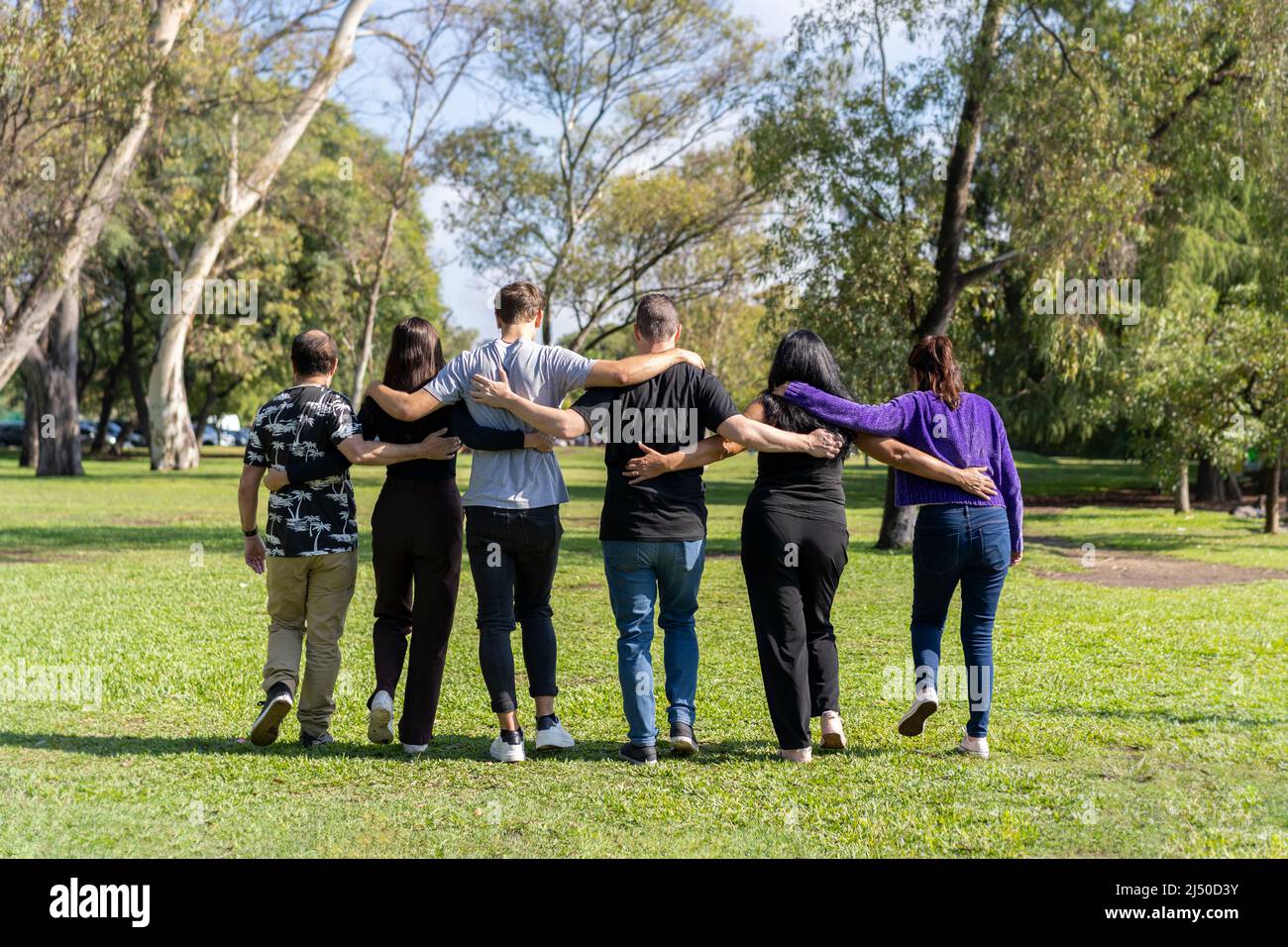 Gruppo multietnico di famiglia che cammina braccio in braccio in un parco. Famiglia, gruppo, lavoro di squadra, concetto di amicizia Foto Stock