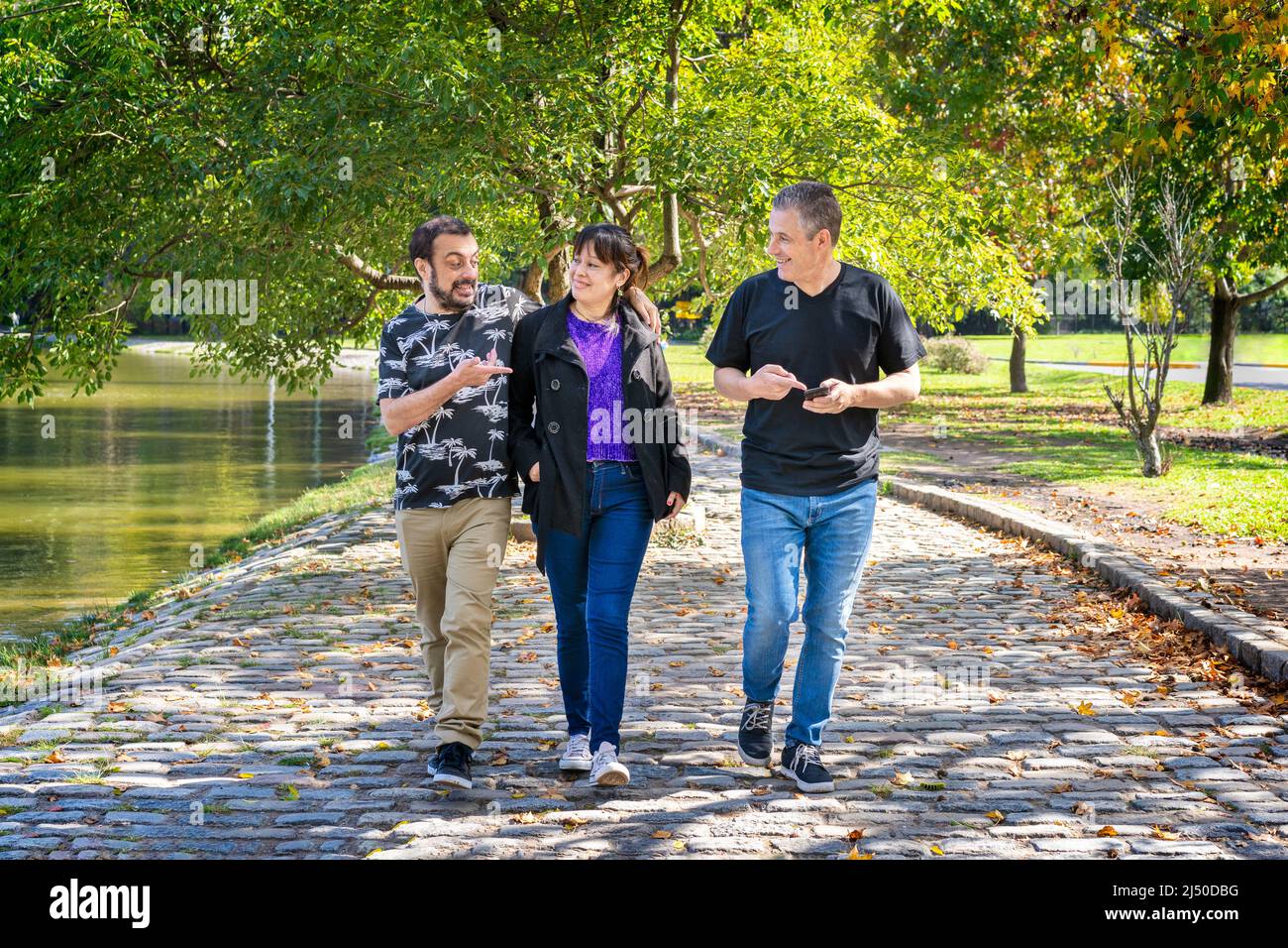 Gruppo di amici che camminano in un parco chiacchierando, ridendo e avendo un buon tempo Foto Stock