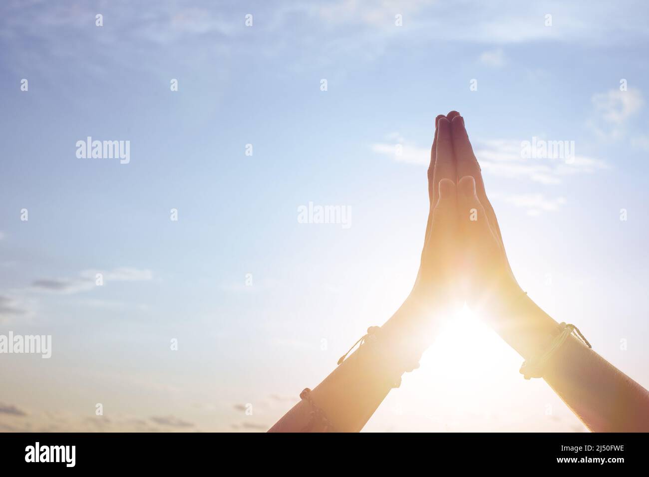 Le mani femminili ringraziano il mondo contro il cielo con il sole Foto Stock