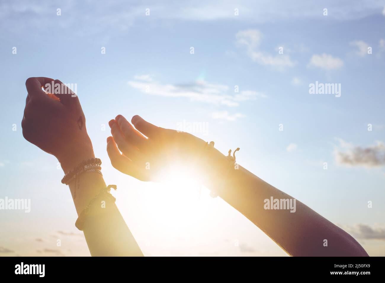 Le mani della donna raggiungono il cielo e chiudono il sole Foto Stock