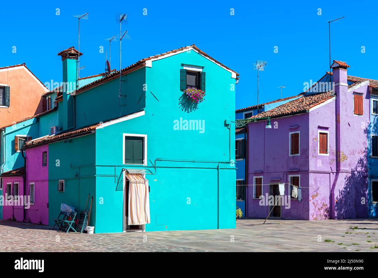 Tipiche case dipinte a colori sotto il cielo blu sull'isola di Burano a Venezia. Foto Stock