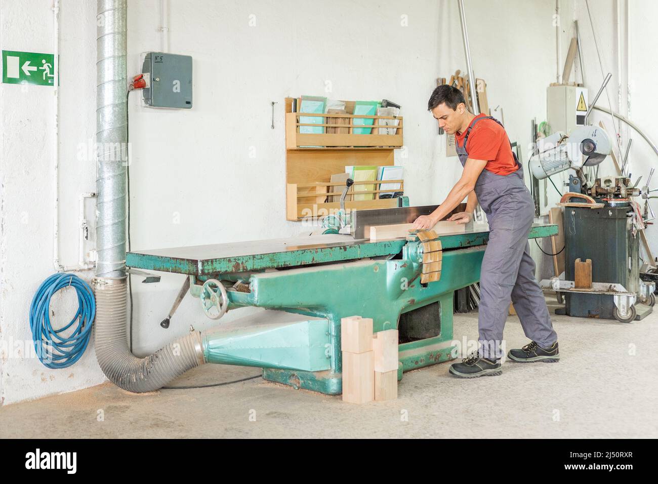 Carpentiere che lavora presso la piallatrice per lavorazione del legno in officina Foto Stock