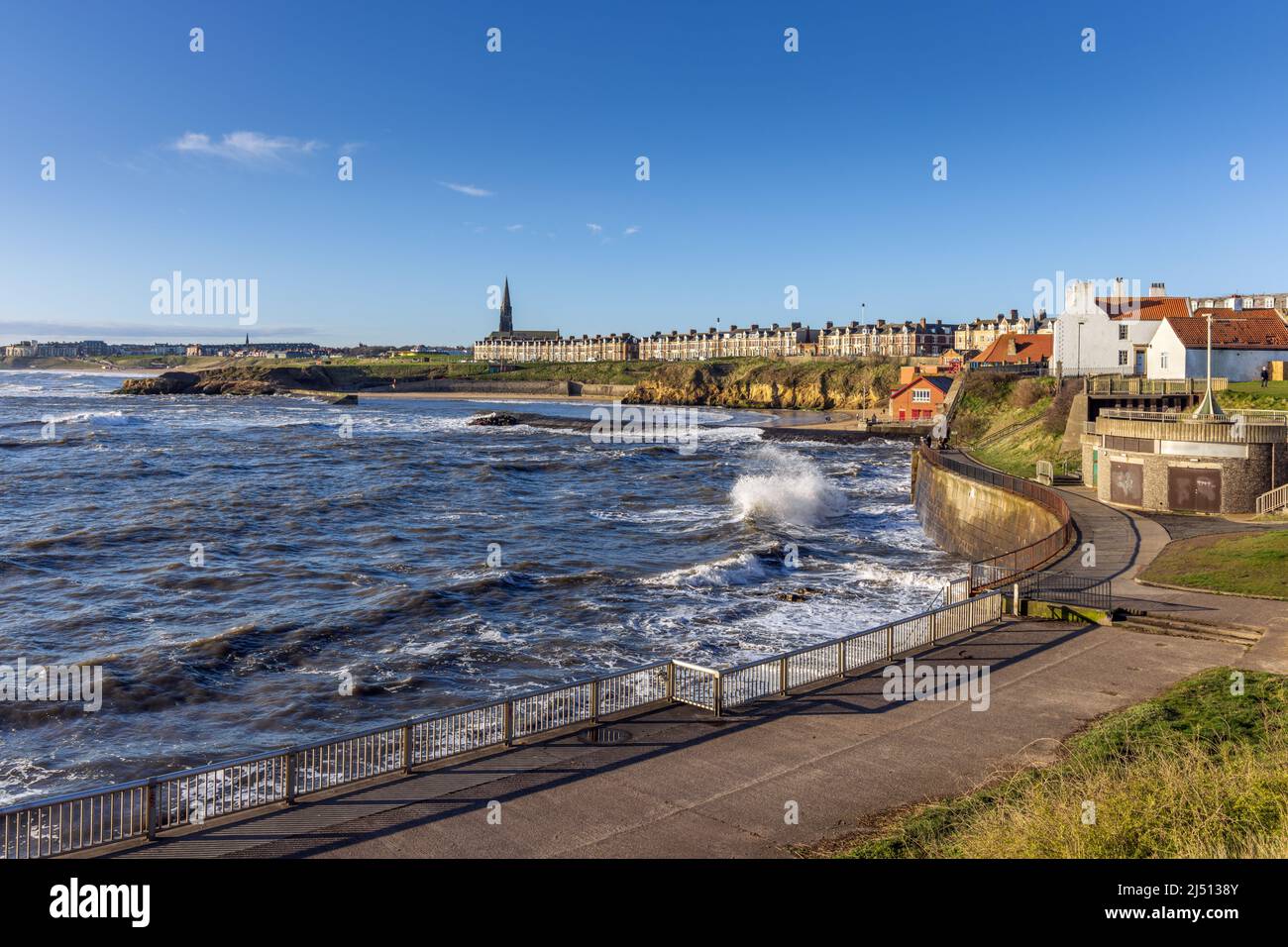 Onde forti ad alta marea che colpiscono le pareti del porto di Cullercoats a North Tyneside la mattina presto della primavera. Foto Stock