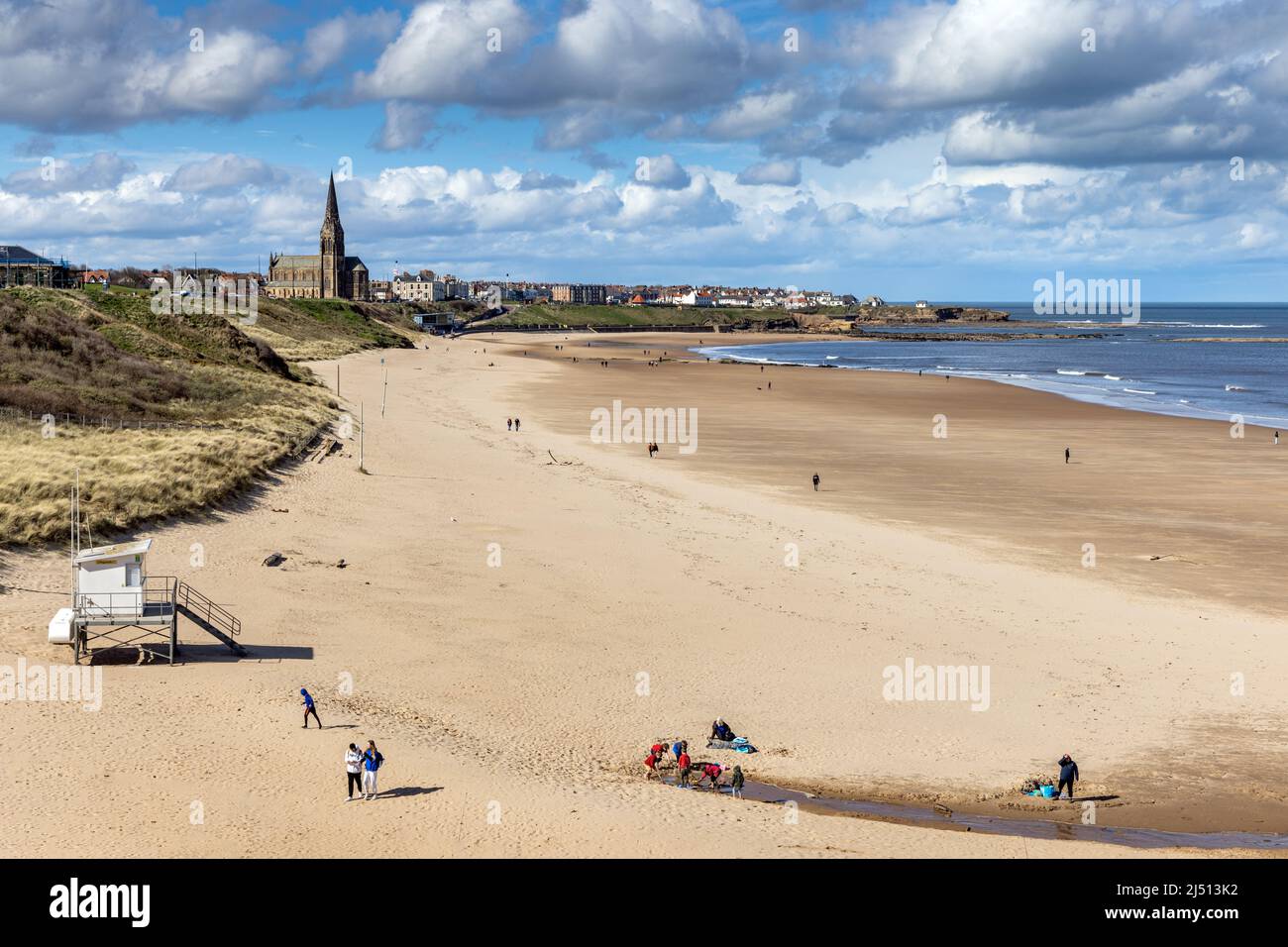 Spiaggia di Long Sands a Tynemouth in una giornata di primavera, con la chiesa di St George a Cullercoats in lontananza, Tyne and Wear, Inghilterra, Regno Unito Foto Stock