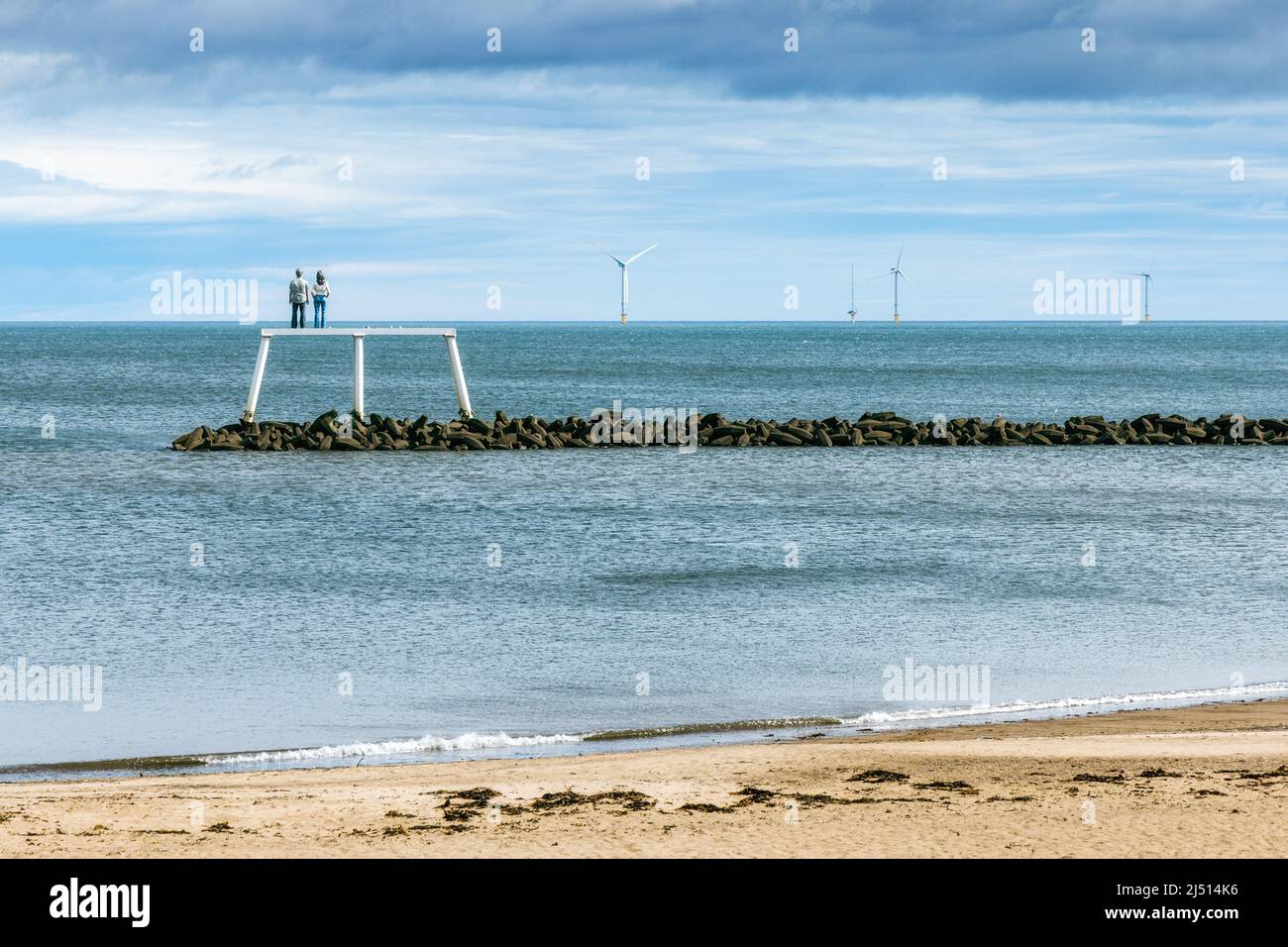 In piedi su un frangiflutti al largo della spiaggia a Newbiggin Bay in Northumberland, 'la coppia' è una scultura alta 12,5 metri dall'artista Sean Henry. Foto Stock