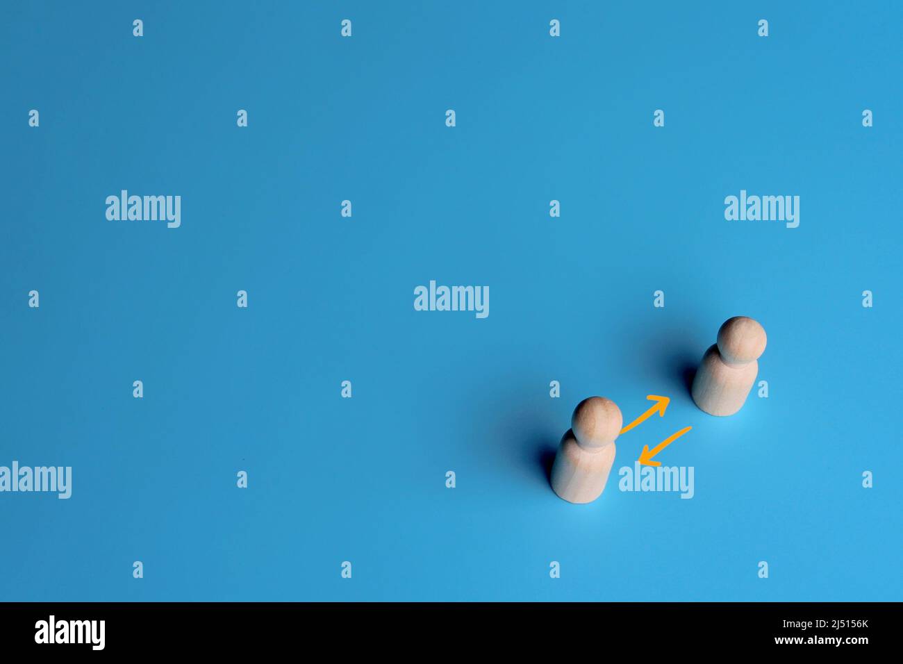 Bambole in legno e freccia di scambio su sfondo blu. Spazio di copia. Concetto di condivisione, rete, peer-to-peer Foto Stock