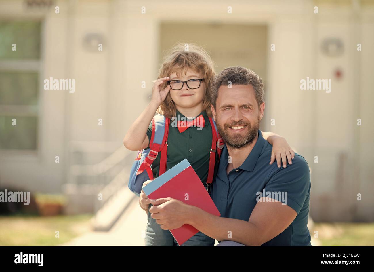 infanzia e genitorialità di padre abbracciando figlio ragazzo vicino a scuola, paternità Foto Stock