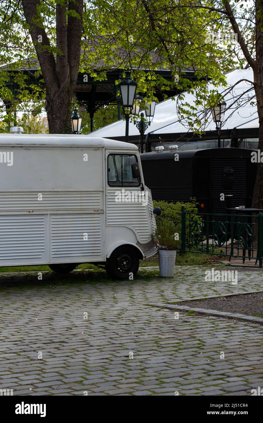 I due furgoni sono parcheggiati sotto gli alberi e proprio accanto ad una rotonda art deco Foto Stock