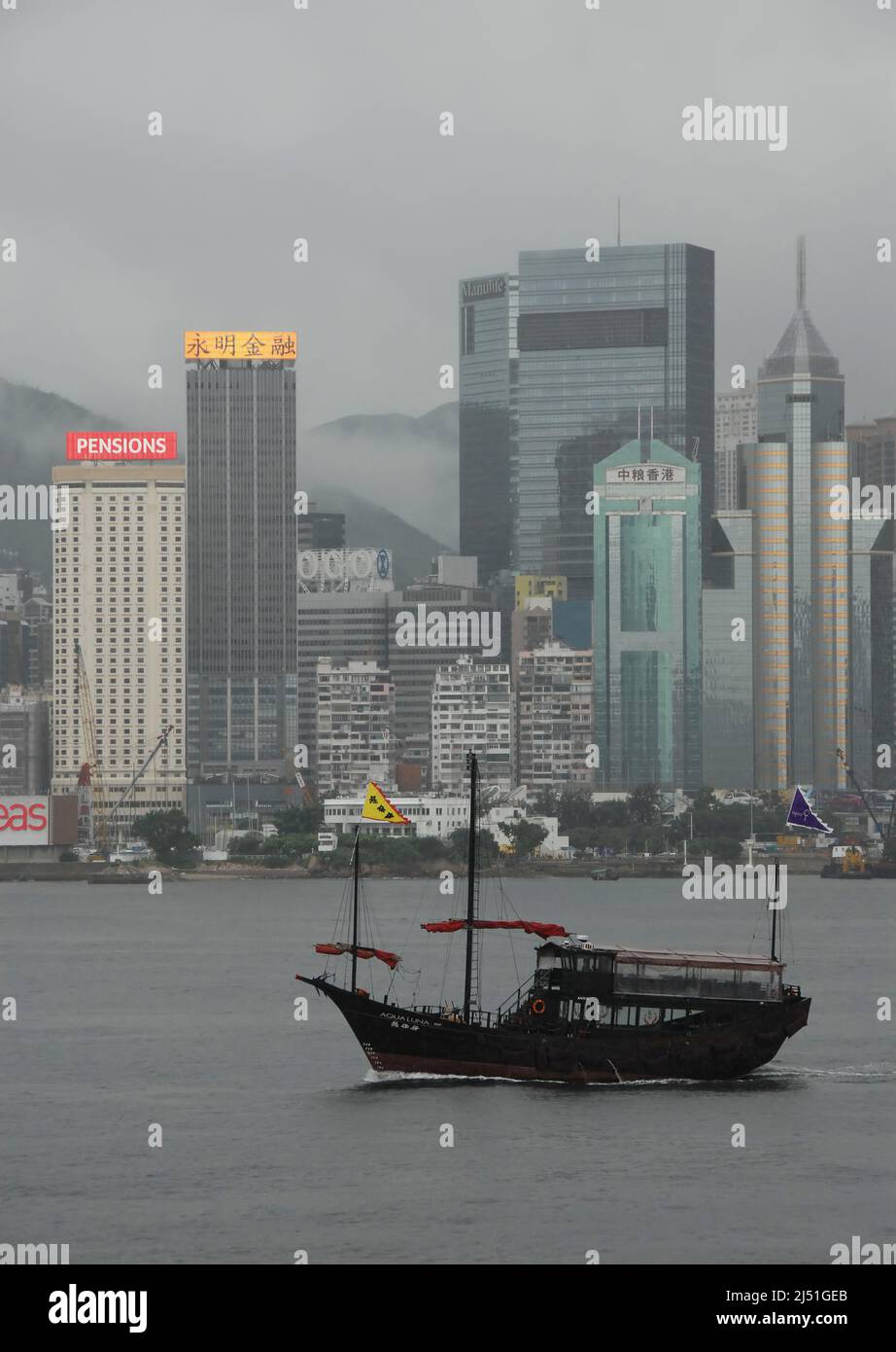 Victoria Harbour, Hong Kong, Cina: Vista attraverso Victoria Harbour verso i distretti di WAN Chai e Causeway Bay di Hong Kong con junk boat. Foto Stock