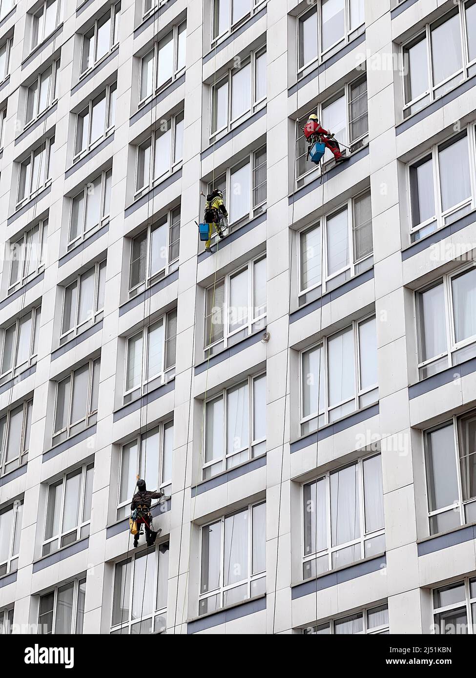 Gli scalatori industriali lavano le finestre su un enorme edificio residenziale. Lavorare in quota richiede abilità e abilità. Foto Stock
