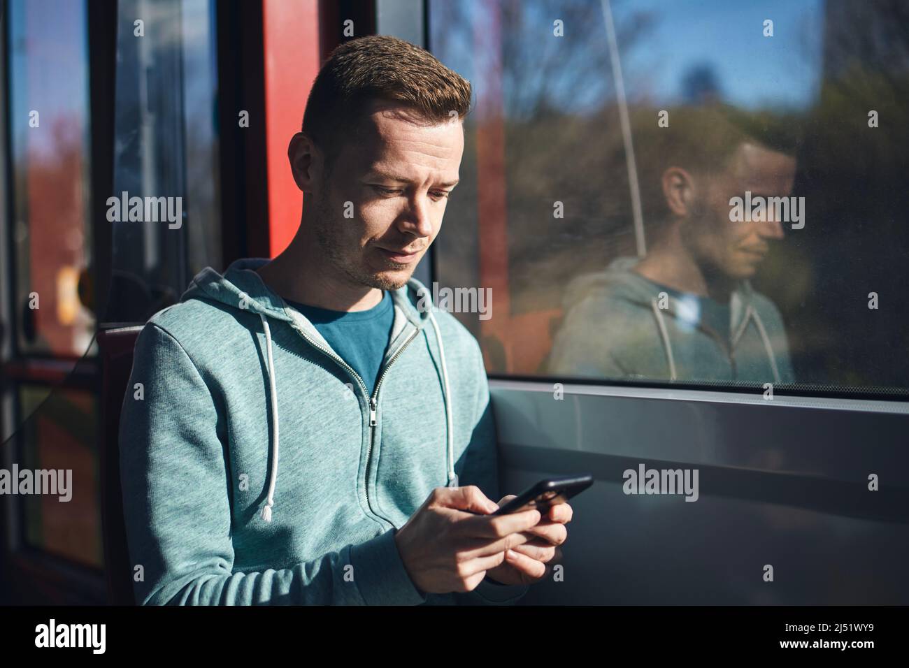 Uomo che usa il telefono mentre si è in viaggio con il tram dei mezzi pubblici. Foto Stock