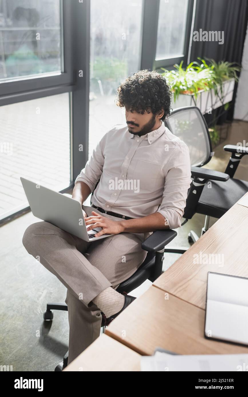 Giovane uomo d'affari indiano che usa il laptop in ufficio Foto Stock
