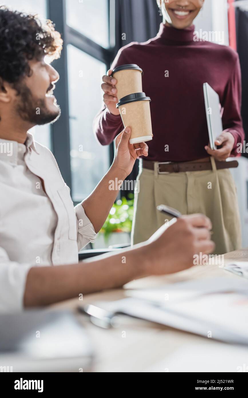 Uomini d'affari multietnici che tengono il caffè per andare mentre lavorano in ufficio Foto Stock