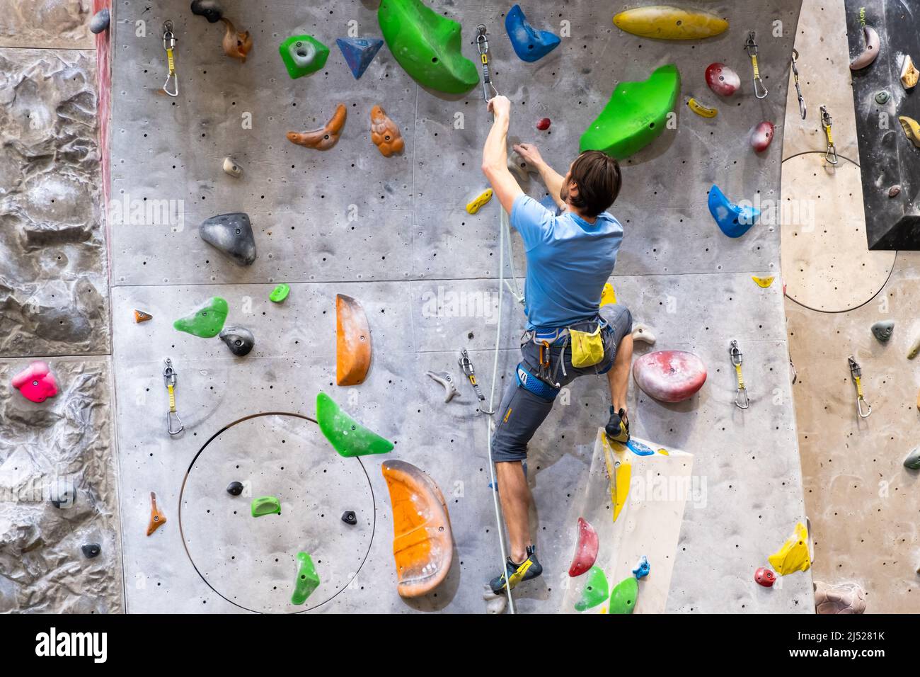 Il climber si allena sul muro di roccia artificiale con assicurazione in palestra di bouldering, aprile 2022, Praga, Repubblica Ceca. Foto Stock