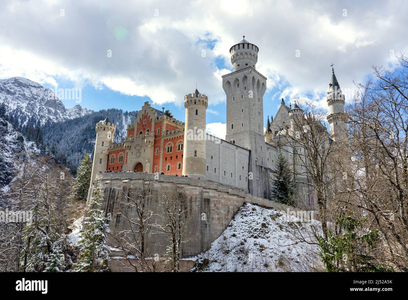 Castello di Neuschwanstein in un bel paesaggio invernale ghiacciato con nuvole e sole Foto Stock