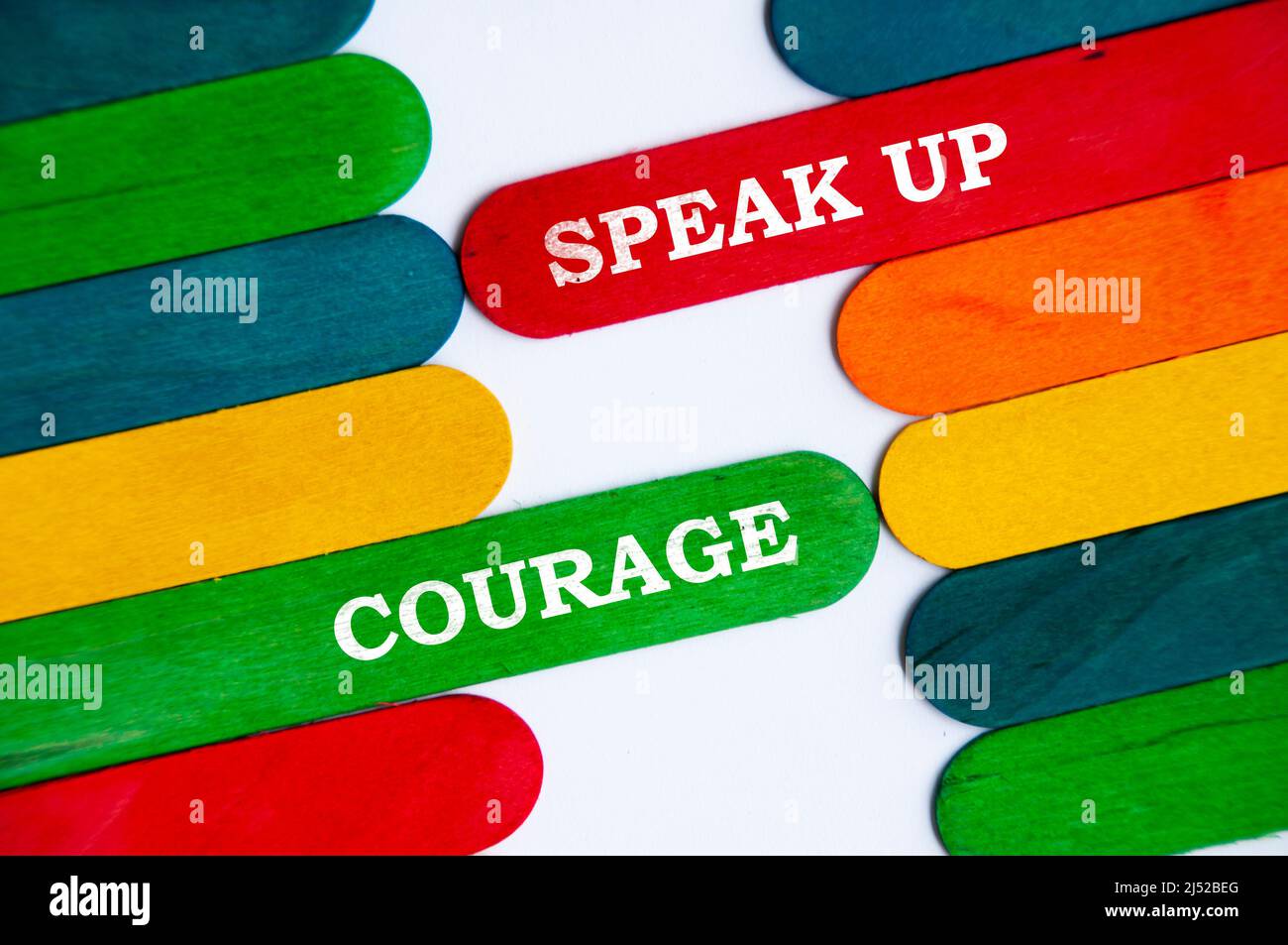 Parlate e testo di coraggio sul colorato bastone di legno - concetto di business Foto Stock