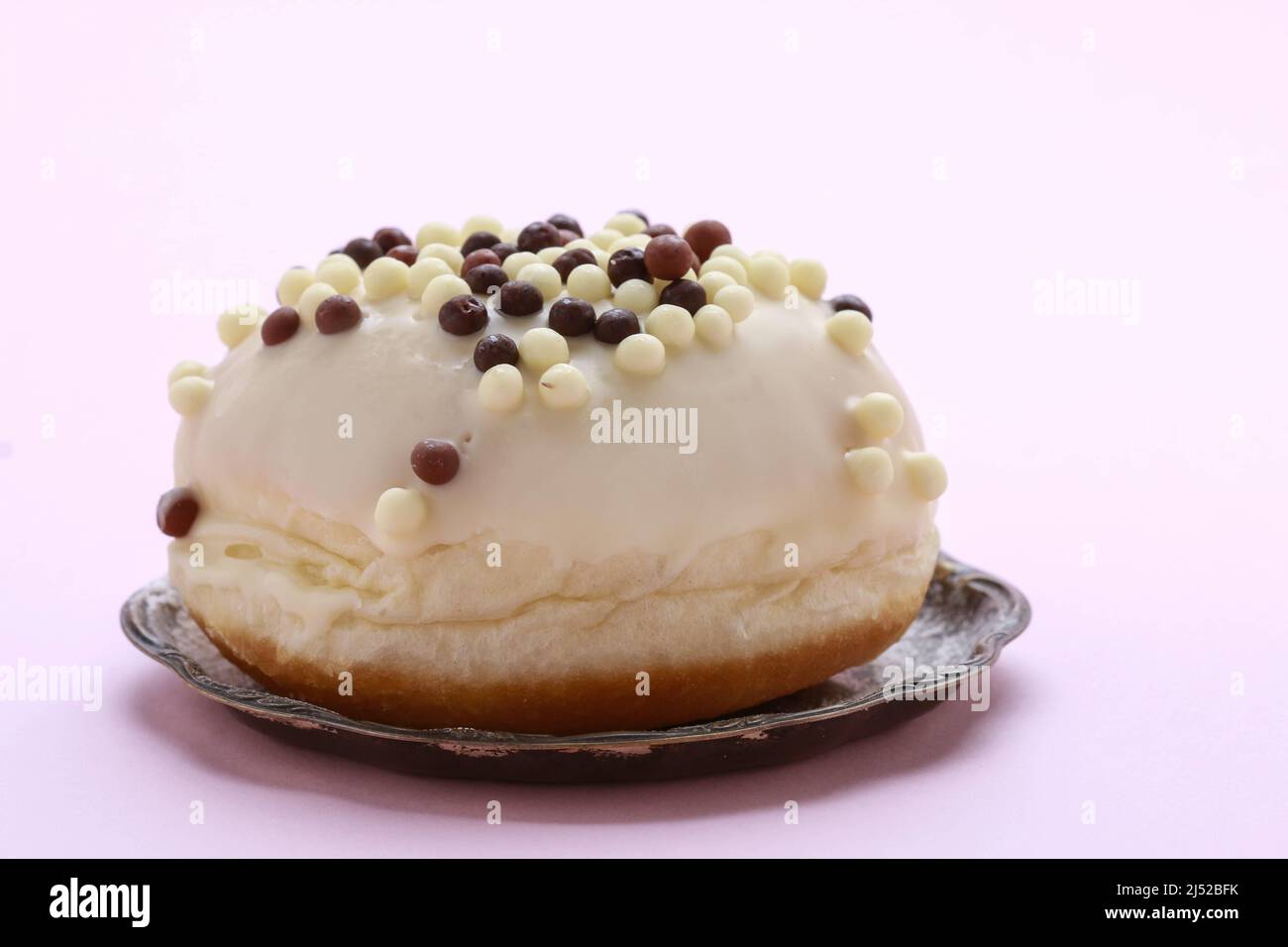 Una ciambella in cioccolato bianco su sfondo rosa. Dessert party Foto Stock
