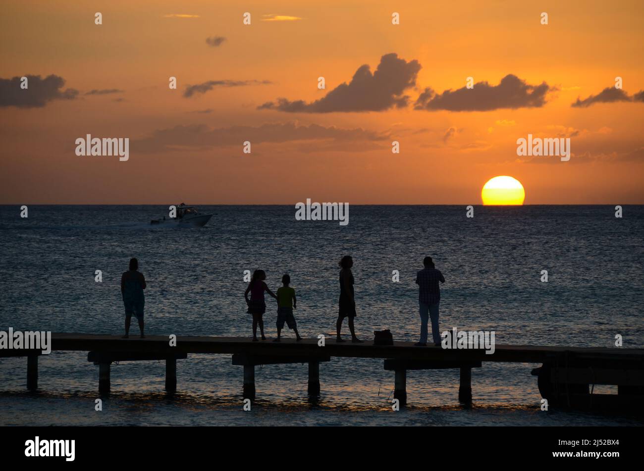 La famiglia guarda il tramonto sul molo dei Caraibi tropicali Foto Stock