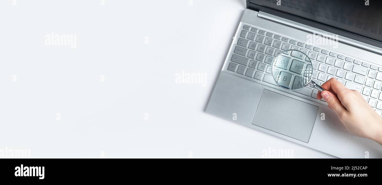 Banner con una mano donna che tiene la lente di ingrandimento sulla tastiera del laptop. Ricerca di informazioni su Internet Concept. Esperienza di progetti elettronici, dati finanziari. Spazio per il testo. Foto di alta qualità Foto Stock