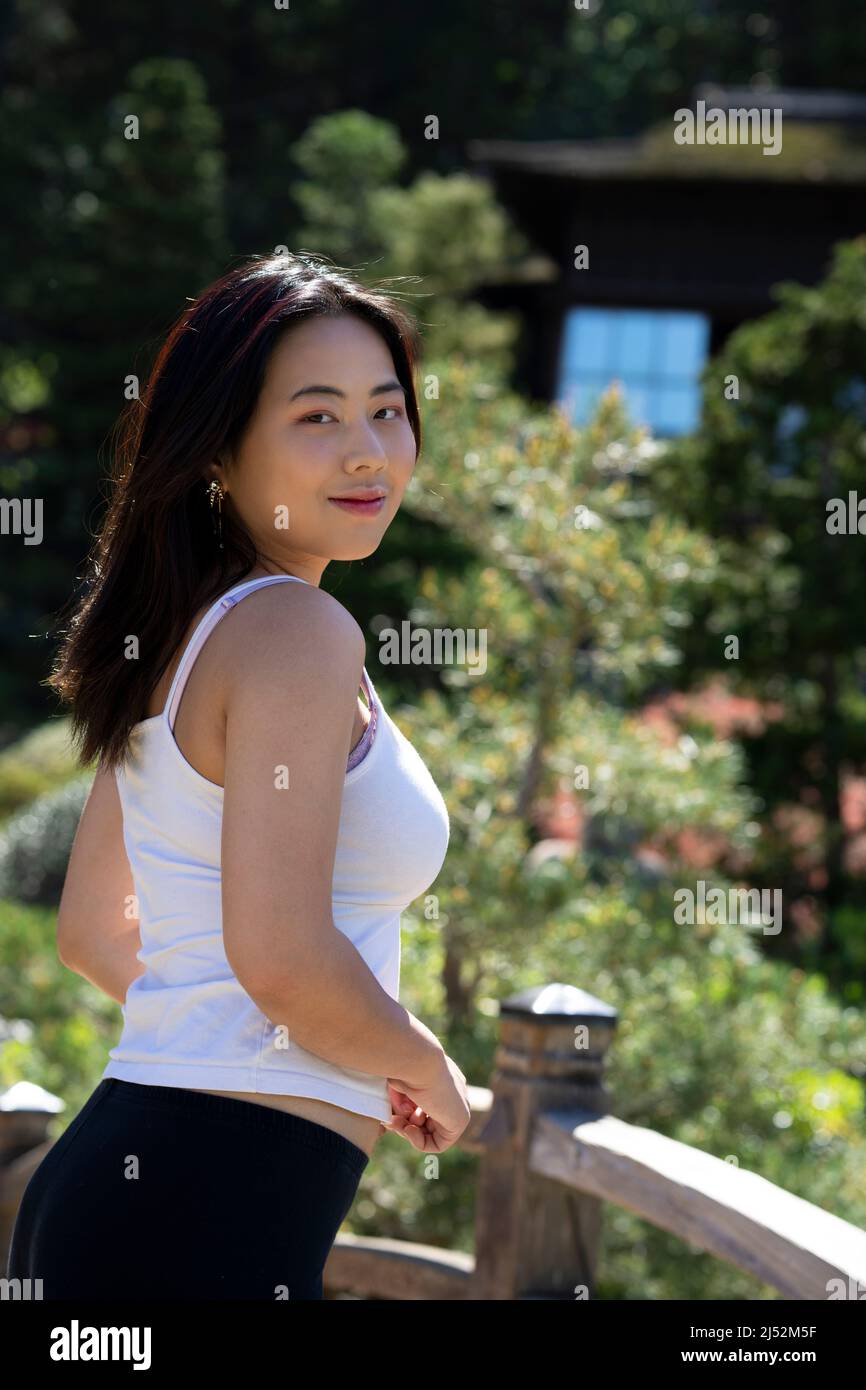 Giovane donna in abiti casual su un ponte su un laghetto giapponese Koi Foto Stock