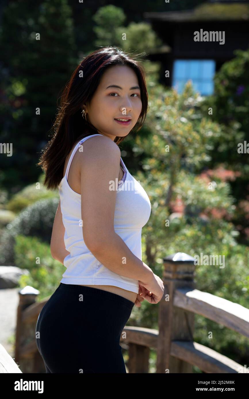 Giovane donna in abiti casual su un ponte su un laghetto giapponese Koi Foto Stock