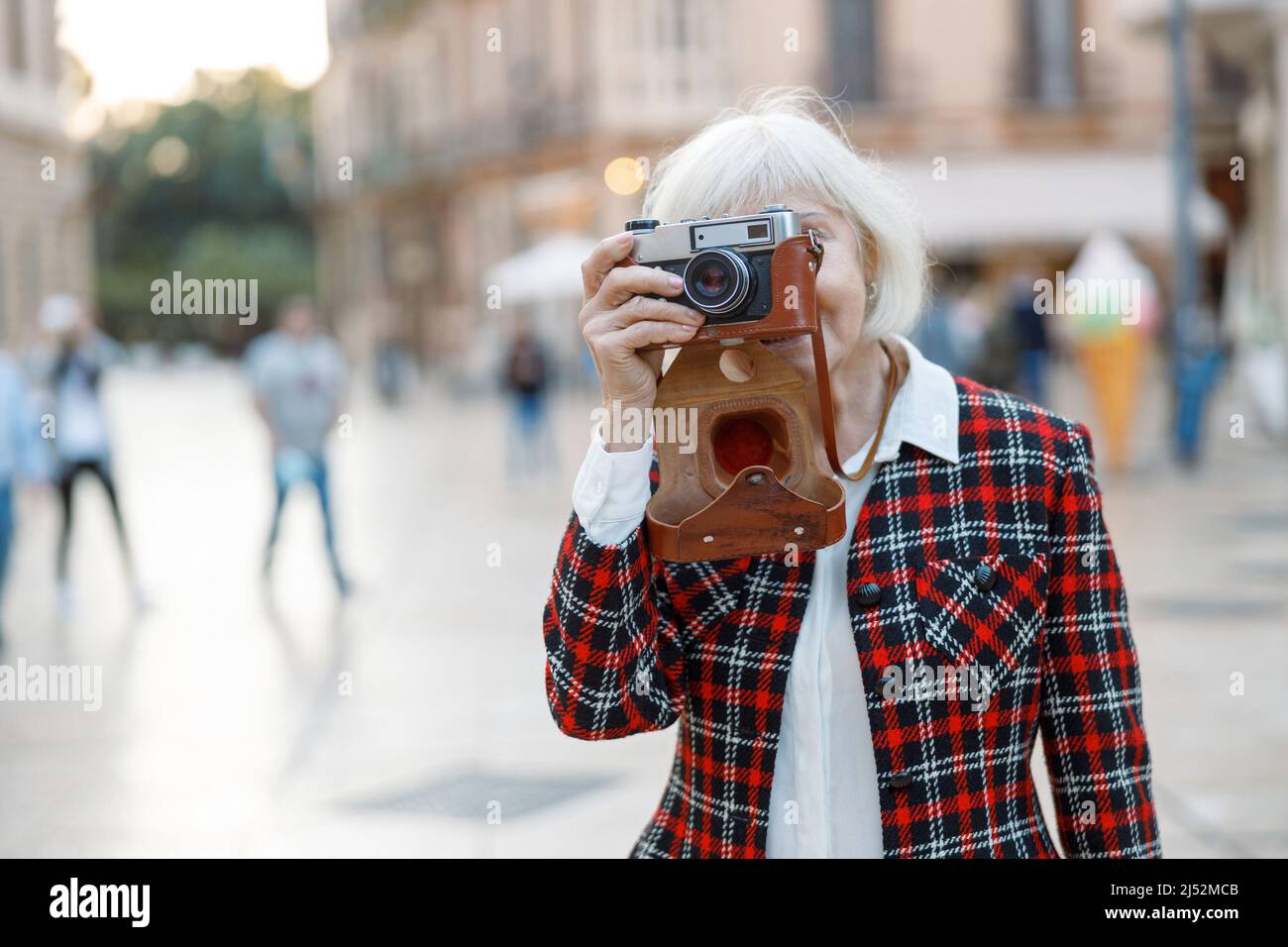 Donna anziana impegnata facendo una passeggiata attraverso la città Foto Stock