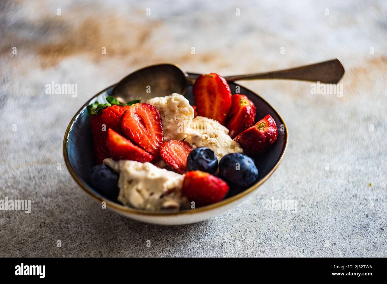 Ciotola di gelato alla vaniglia con mirtilli freschi e fragole Foto Stock