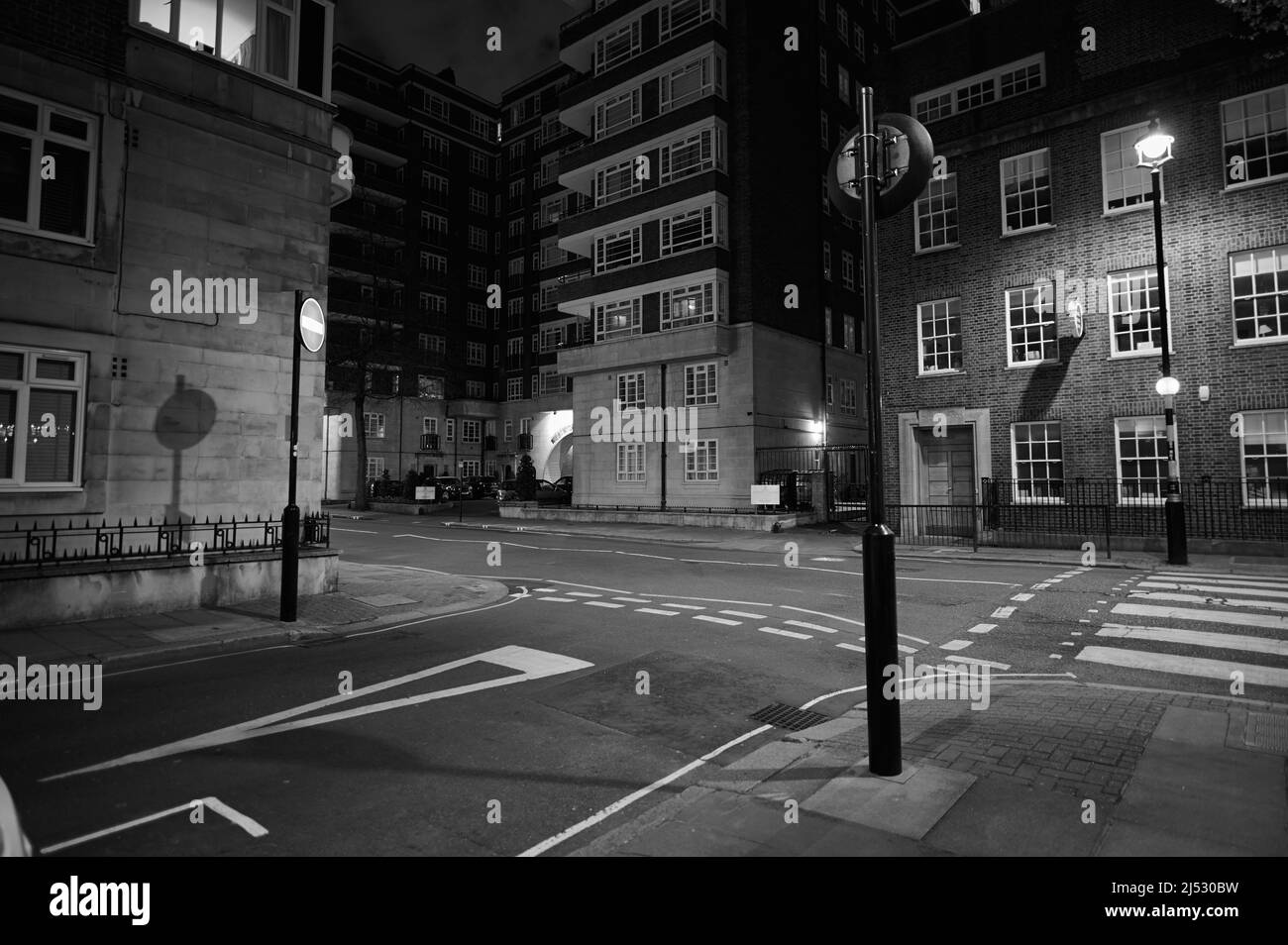 13 aprile 2022 - londonuk : bianco e nero scena stradale a londra di zebra attraversamento pedonale e incrocio t con grande condominio Foto Stock