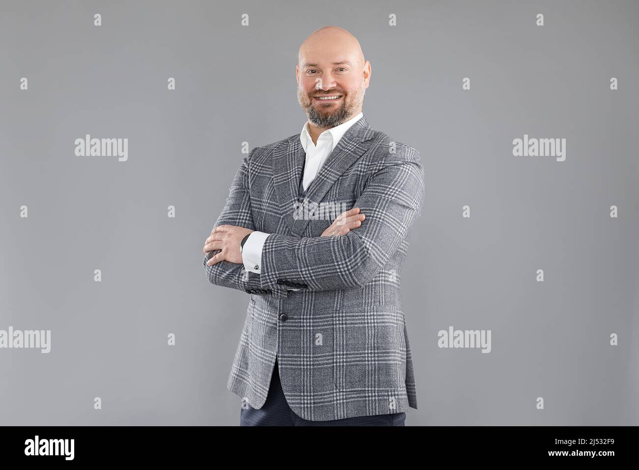 Ritratto di allegro uomo d'affari di mezza età in giacca a scacchi grigia, gilet, camicia bianca, in piedi con le braccia incrociate. Foto Stock