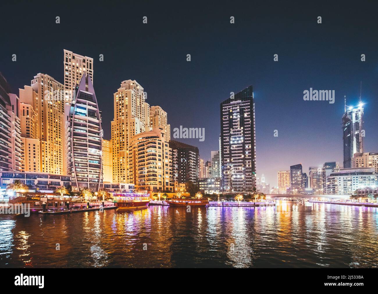 Vista notturna degli alti edifici del quartiere residenziale a Dubai Marina e Barca turistica, Barca turistica vela a Dubai Marina Foto Stock