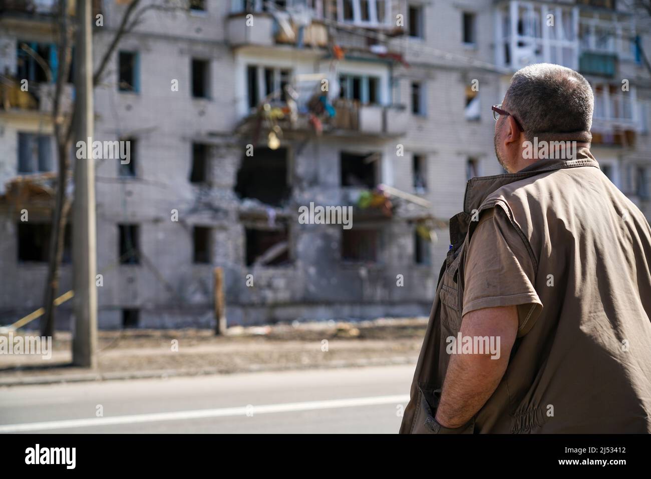 Un uomo si trova vicino a una casa distrutta che è stata colpita da una conchiglia di operazioni militari in Ucraina Foto Stock