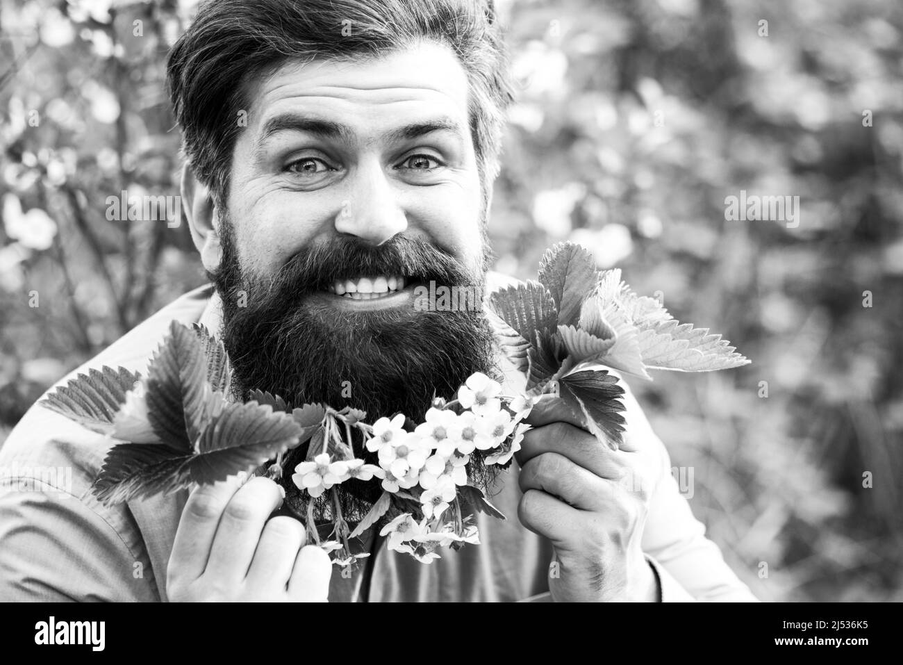 Un ritratto di uomo felice con fiori bianchi sulla testa. Foto di moda Spring mans. Foto Stock