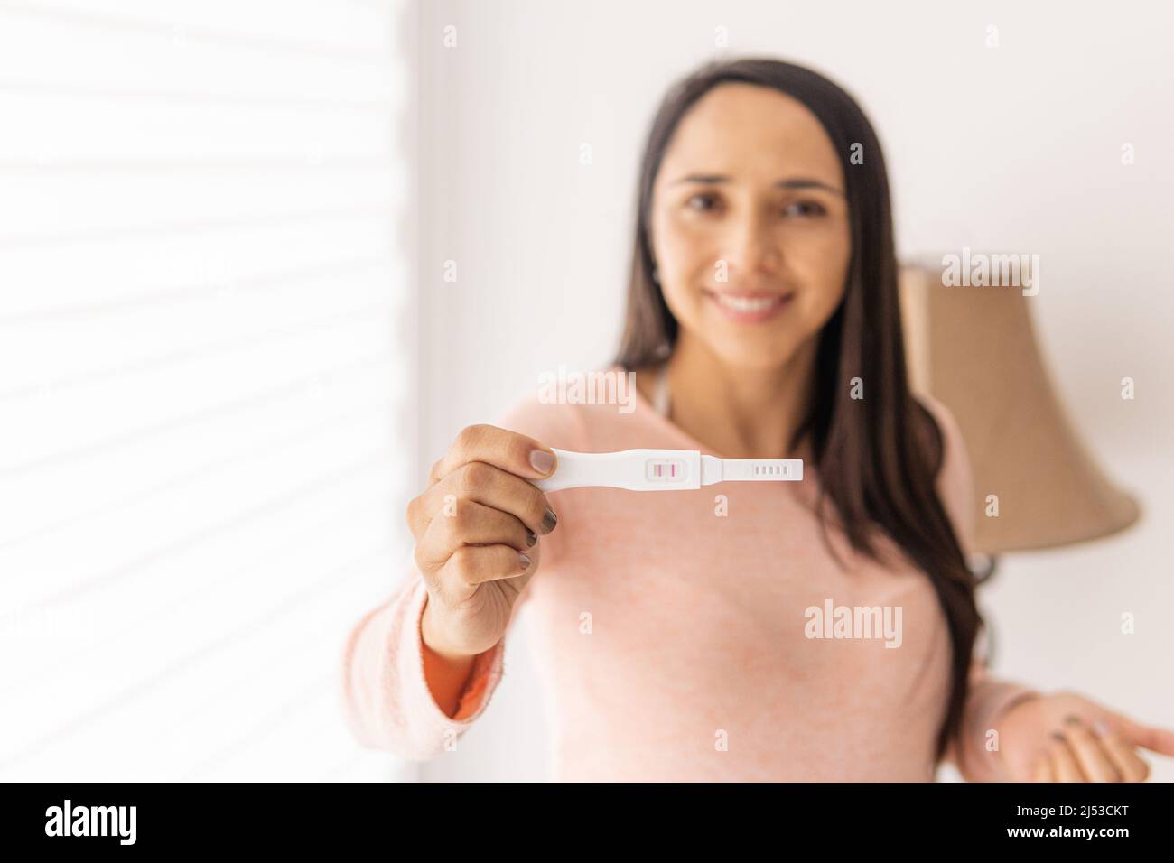 Primo piano di una mano di una donna latina che tiene un test di gravidanza Foto Stock