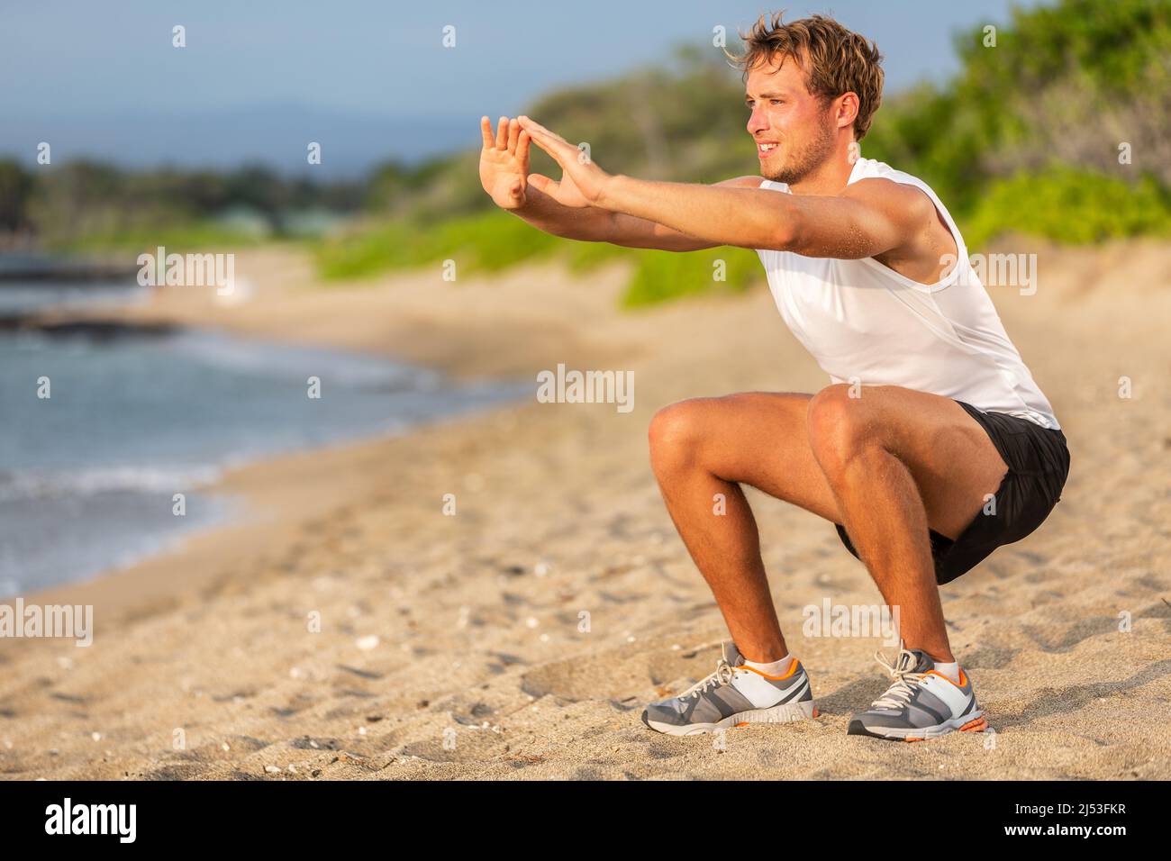 Fitness allenamento allenamenti allenamento forza uomo facendo squat sulla spiaggia. Le gambe del corpo inferiore esercitano l'atleta Foto Stock