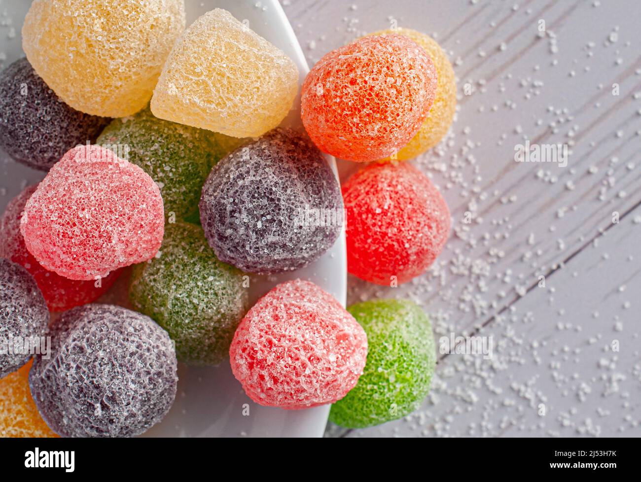 caramelle, gommie in diversi sapori e colori su un piatto bianco e un tavolo bianco. Fotografia macro Foto Stock