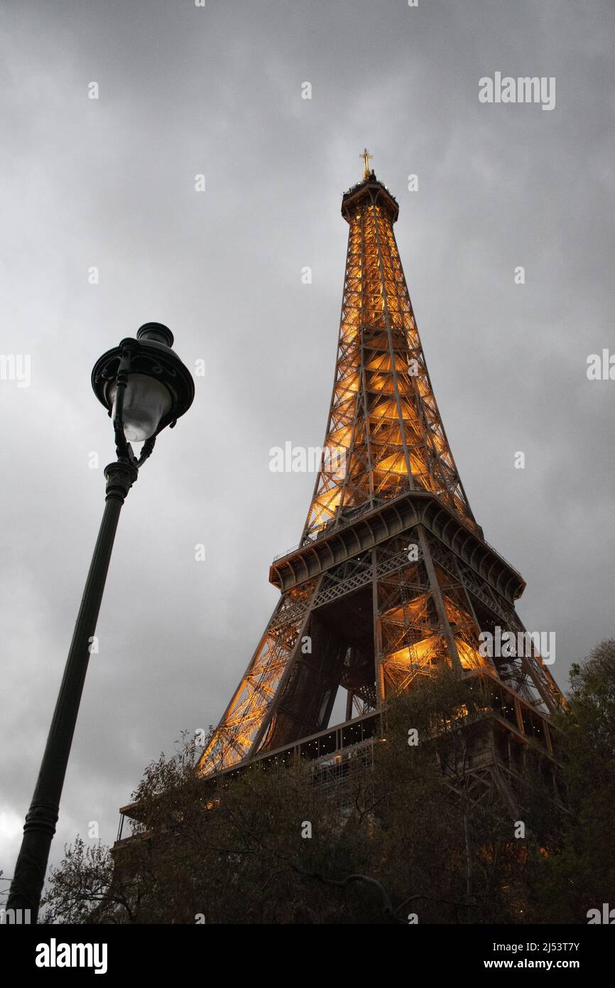 Parigi, Francia: Una lampada da strada e la Torre Eiffel, torre di metallo completata nel 1889 per l'esposizione universale, visto illuminato in una serata nuvolosa Foto Stock