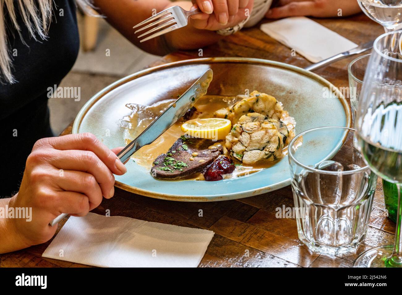 Ragazza (parte di persona) che mangia tradizionalmente cibo ceco 'salsa di 'svickova', manzo e gnocchi al ristorante. Foto Stock
