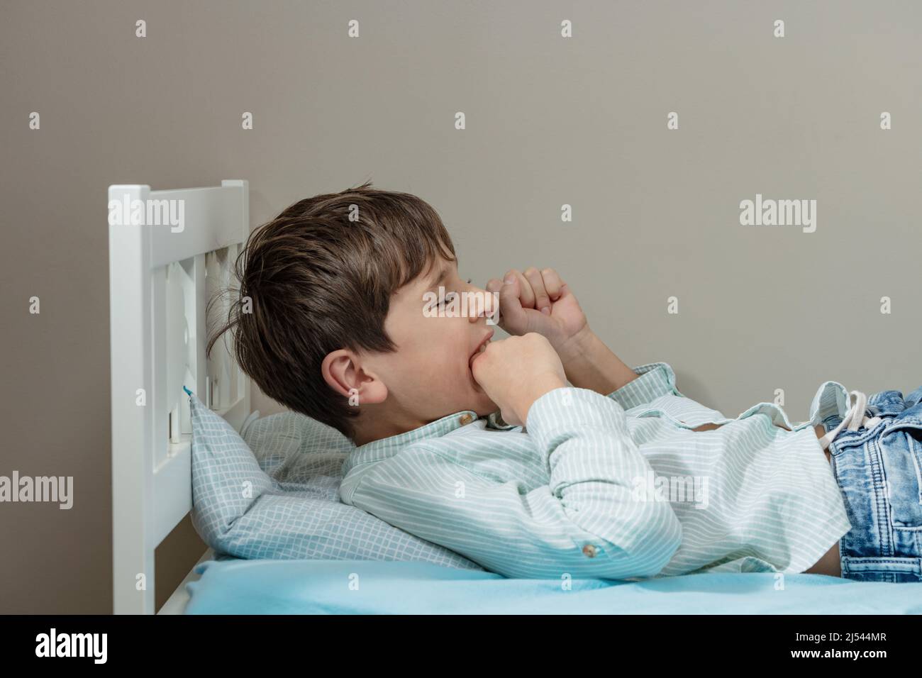 Il ragazzo autistico morde la mano con forte espressione negativa del volto Foto Stock