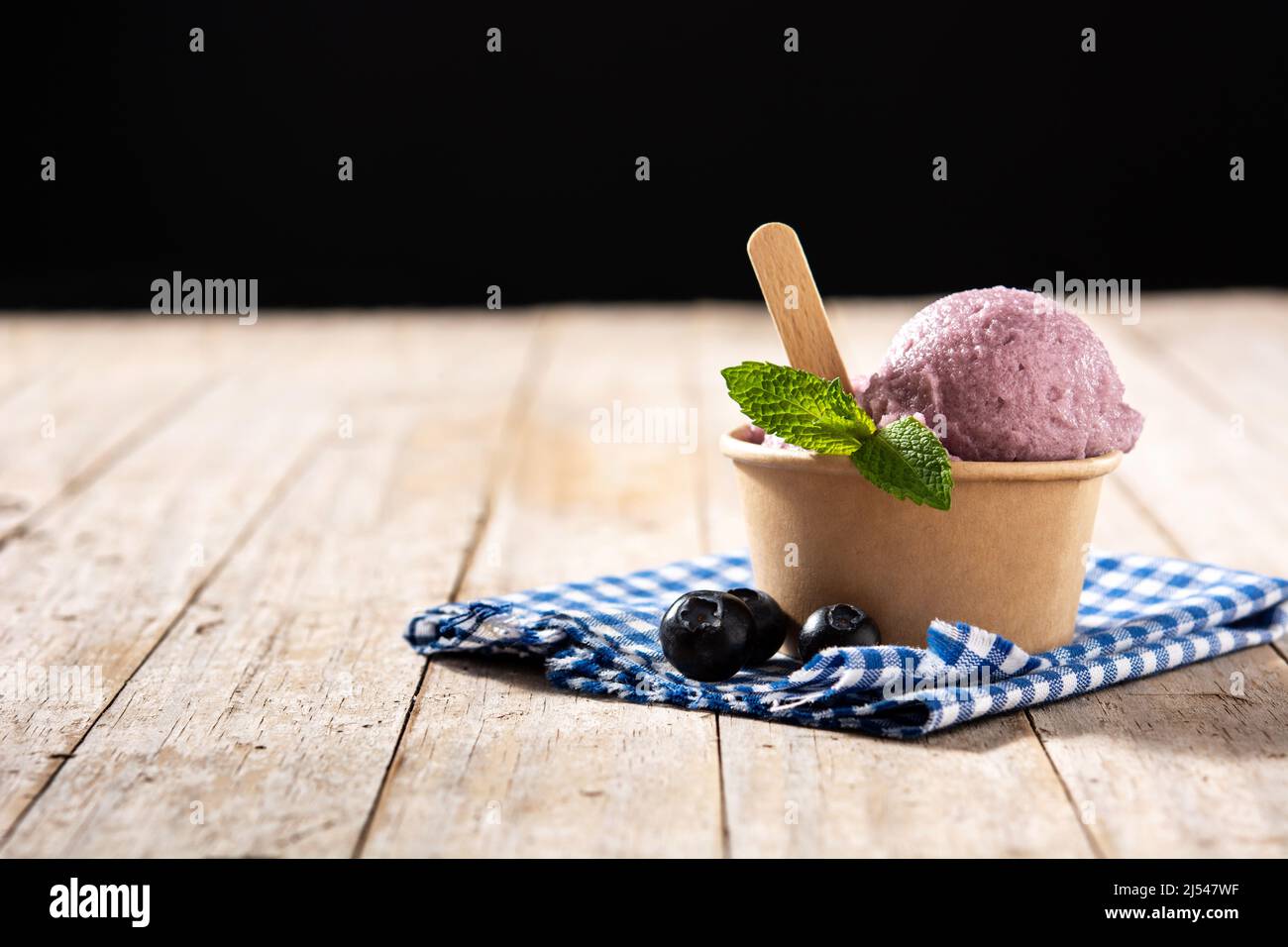 Cucchiaio per gelato al mirtillo su tavola di legno Foto Stock