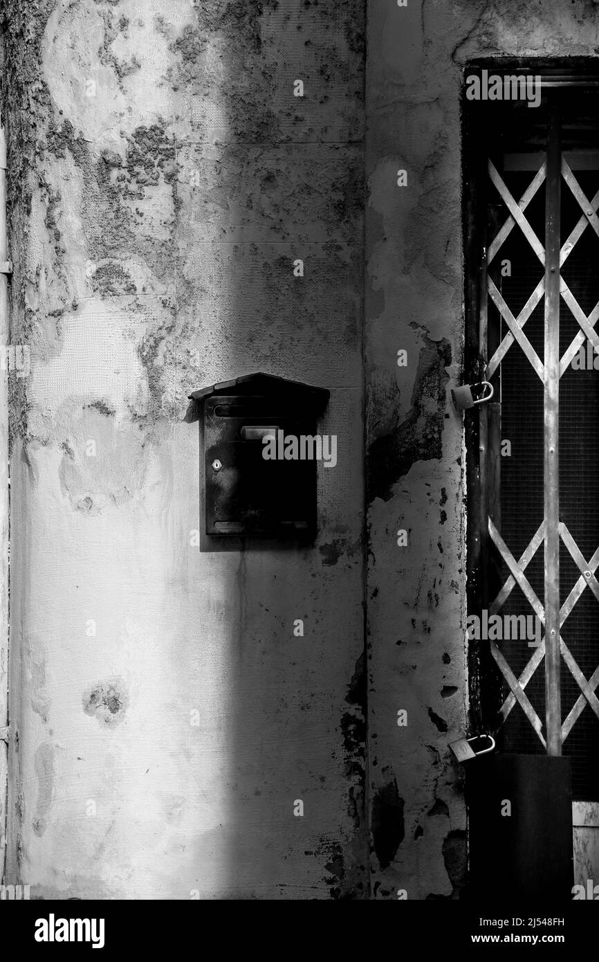 Cassetta postale nera sulla facciata a schegge accanto alla porta con traliccio in metallo Foto Stock