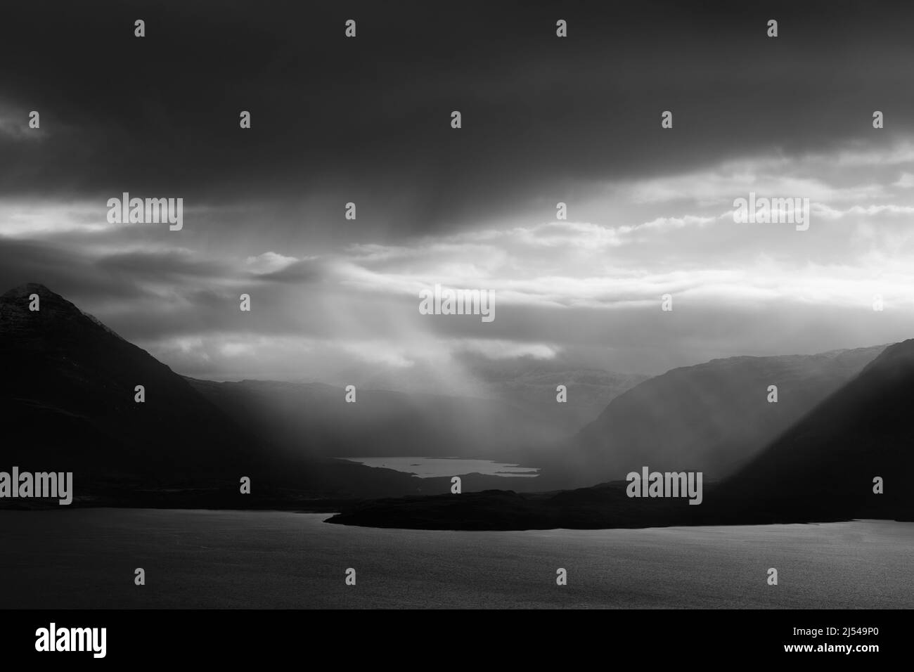 Sole che cattura una doccia a slitta su Loch Damh con Loch Torridon in primo piano, Highlands scozzesi Foto Stock