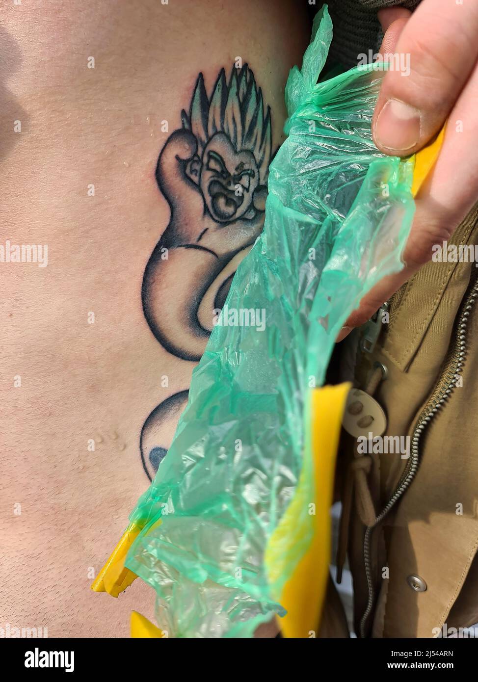 uomo che rimuove il foglio protettivo da un tatuaggio appena inchiostrato Foto Stock