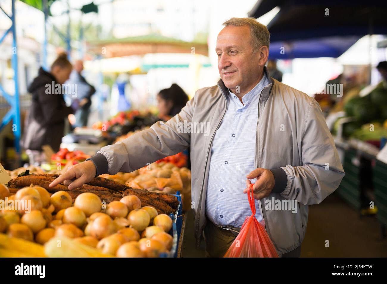 Uomo che sceglie le verdure in greengrocery Foto Stock