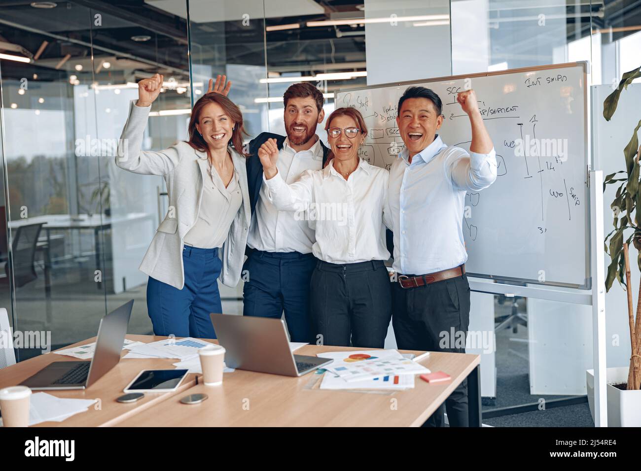 Il team sorridente che si pone per scattare foto sul posto di lavoro, ha motivato i colleghi diversi a mostrare unità Foto Stock
