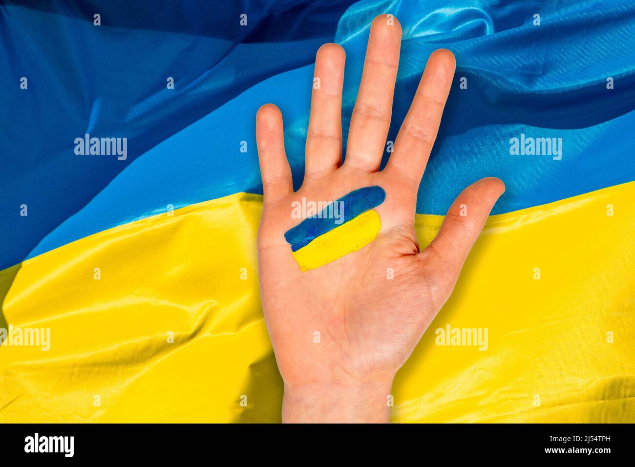 Mano con tratti di pennello blu e giallo sullo sfondo della bandiera Ucraina Foto Stock
