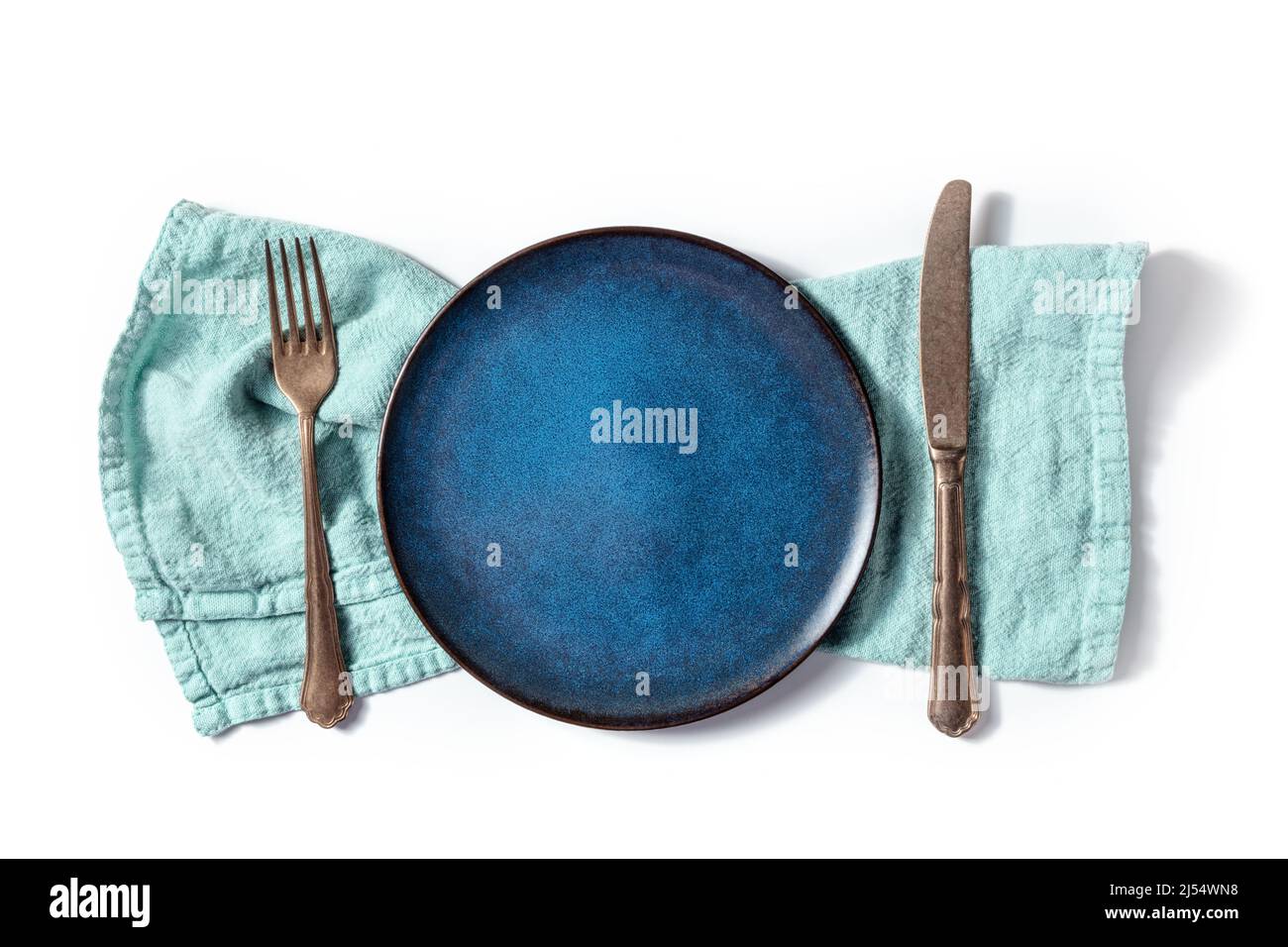 Posate con piatto blu. Una forchetta, un coltello, e un piatto su un tovagliolo in teal, sopra piano steso sparato su uno sfondo bianco Foto Stock